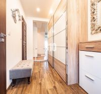 Flur mit Holzboden, Schränken und Spiegel in einem Einfamilienhaus.