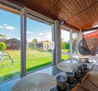 Eine verglaste Terrasse eines Einfamilienhauses in Nitra mit Blick auf den Garten und Holzelementen.
