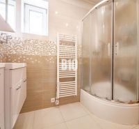 Badezimmer in einem Einfamilienhaus mit einer Eckdusche und hellen Fliesen.