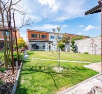 Ein Garten bei einem Einfamilienhaus in Nitra mit Rasen, Blumen und Terrasse.