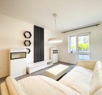 Wohnzimmer in einer 2-Zimmer-Wohnung mit Holzboden und weißen Möbeln.