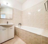 Badezimmer in einer 2-Zimmer-Wohnung mit Badewanne und Waschbecken, gefliest.