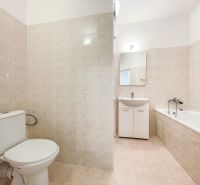 Badezimmer in einer 2-Zimmer-Wohnung mit Waschbecken, Badewanne und weißen Fliesen.
