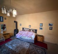 Ein Schlafzimmer in einem Einfamilienhaus mit Kachelofen, Bett und dekorativen Bildern an der Wand.