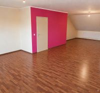 Wohnzimmer in einem Einfamilienhaus mit Holzboden und rosa Wand.