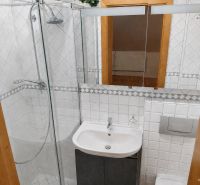 Ein Badezimmer in einem Einfamilienhaus mit weißen Fliesen und einer Duschkabine.