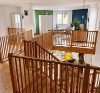 Innenraum eines Einfamilienhauses mit Holzboden und Holzgeländer.