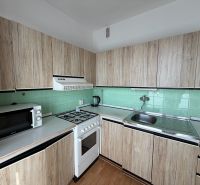 Küche in einer 3-Zimmer-Wohnung mit Holzboden und Holzschränken.