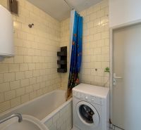 Badezimmer in einer 3-Zimmer-Wohnung mit Badewanne, Waschmaschine und weißen Fliesen.