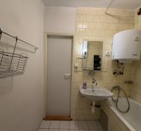 Badezimmer in einer 3-Zimmer-Wohnung mit Waschbecken, Badewanne und Wassererhitzer an der Wand.