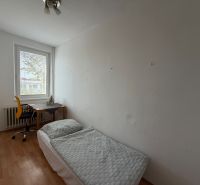 Ein Zimmer in einer 3-Zimmer-Wohnung mit einem Bett, einem Tisch und einem Boden in Holzoptik.