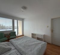 Schlafzimmer in einer 3-Zimmer-Wohnung mit Holzboden, Bett und Sesseln.