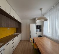Eine Küche mit Holzboden, gelben Fliesen und einem Esstisch in einer 3-Zimmer-Wohnung.