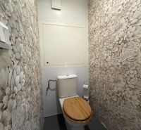 Toilette mit Blumen-Tapeten und einem Holzsitz in einer 3-Zimmer-Wohnung.