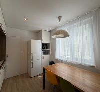 Küche mit weißem Kühlschrank, bunten Stühlen und Holzboden in einer 3-Zimmer-Wohnung.
