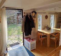 Ein Holztisch und Stühle in einer Hütte mit Blick auf den Garten.