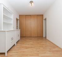 Der Flur in der 3-Zimmer-Wohnung mit einem weißen Schrank und einem Boden in Holzoptik.
