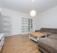 Wohnzimmer in einer 3-Zimmer-Wohnung mit Holzboden, Sofa und Bücherregal.
