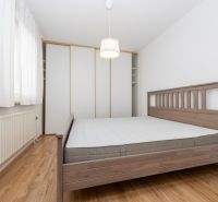 Schlafzimmer in einer 3-Zimmer-Wohnung mit einem Holzbett und einem Boden mit Holzdekor.