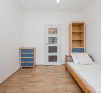 Einfaches Zimmer mit Bett, Schrank und Boden in Holzoptik in einer 3-Zimmer-Wohnung.