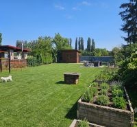 Garten in Kamenný Mlyn, Trnava mit grünem Rasen und Hochbeeten.