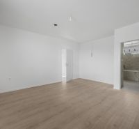 Ein ausdrucksloses Zimmer in einem Einfamilienhaus mit Holzboden und weißen Wänden.