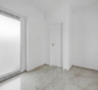 Weißer Eingangsbereich im Einfamilienhaus mit Fliesen und Türen.