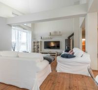 Ferienwohnung mit weißen Sofas und Holzboden, helle Umgebung.