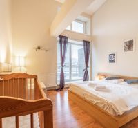 Helles Schlafzimmer im Ferienapartment mit Kinderbett und Holzboden.