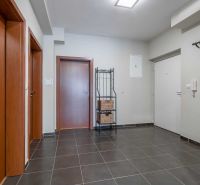 Eingangsbereich einer Ferienwohnung mit dunklen Fliesen, Holztüren und Garderobe.