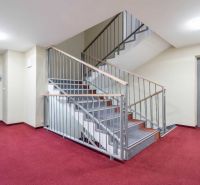 Flur in einem Ferienapartment mit rotem Teppich, Treppe und Aufzug.