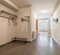 Der Flur des Ferienapartments mit Fliesen, einem Spiegel und einer Garderobenwand.