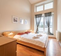 Helles Schlafzimmer mit Doppelbett und Holzboden in einer Ferienwohnung.