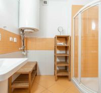 Badezimmer mit orangefarbenen Fliesen, Duschkabine und Waschbecken in einer Ferienwohnung.