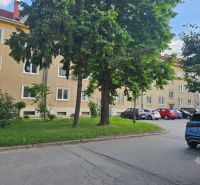 Parkplatz bei den 3-Zimmer-Wohnungen in der Študentská-Straße in Trnava, umgeben von Grünflächen und Bäumen.