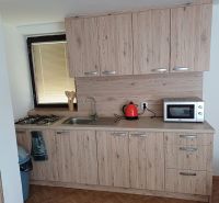 Küche mit Holzboden, Schränke mit Holzdekor und Geräte.
