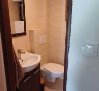 Badezimmer in der Hütte mit Waschbecken, Toilette und hellen Fliesen.