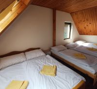 Dachzimmer in der Hütte mit fünf Betten und Holzdach.