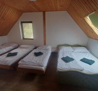 Ein Schlafzimmer in einer Hütte mit drei Betten und einem Boden in Holzoptik.