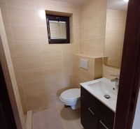 Badezimmer mit hellen Fliesen, Waschbecken und Toilette in der Hütte.