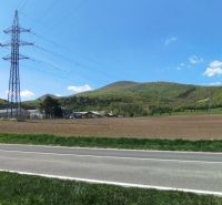 Landschaft an der Továrenská in Smolenice mit landwirtschaftlichen und forstwirtschaftlichen Flächen und Stromleitungen.
