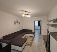 Wohnzimmer mit großem Sofa, Holzboden und schlichtem Interieur in einer 3-Zimmer-Wohnung.