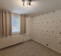 Ein Zimmer in einer 3-Zimmer-Wohnung mit einem Holzboden und einer gepunkteten Tapete.