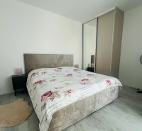 Schlafzimmer in einer 2-Zimmer-Wohnung mit Bett und Schrank, helle Wände, Boden mit Holzdekor.