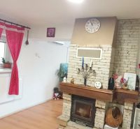 Wohnzimmer in einem Einfamilienhaus mit Kamin und dekorativen Möbeln, Boden mit Holzdekor.