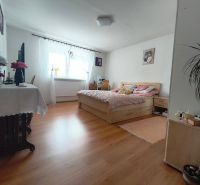 Schlafzimmer im Einfamilienhaus mit Bett und Boden in Holzoptik.