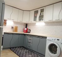 Küche in einem Einfamilienhaus mit weißen und grauen Schränken, Boden mit Holzdekor.