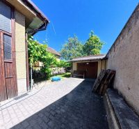 Höfe der Einfamilienhäuser in der Sládkovičova-Straße in Zlaté Moravce, umgeben von Grünflächen und mit Pflastersteinen ausgelegt.