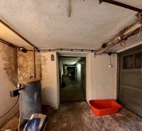 Der Keller eines Einfamilienhauses mit einem Tank und einem orangefarbenen Plastikbehälter auf dem Boden.