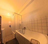 Badezimmer mit Badewanne, Dusche und Fliesen in einem Einfamilienhaus.